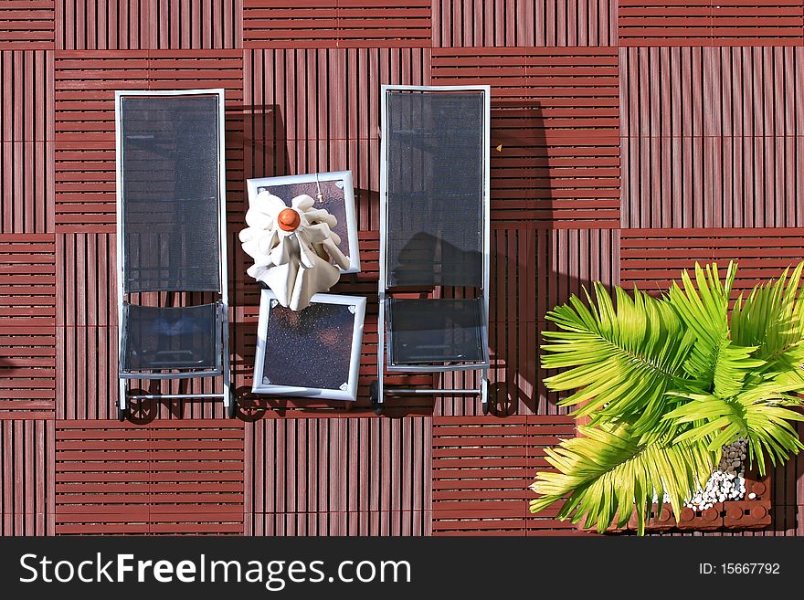 Lounge chairs and Umbrella surround a pool at resort with tree.