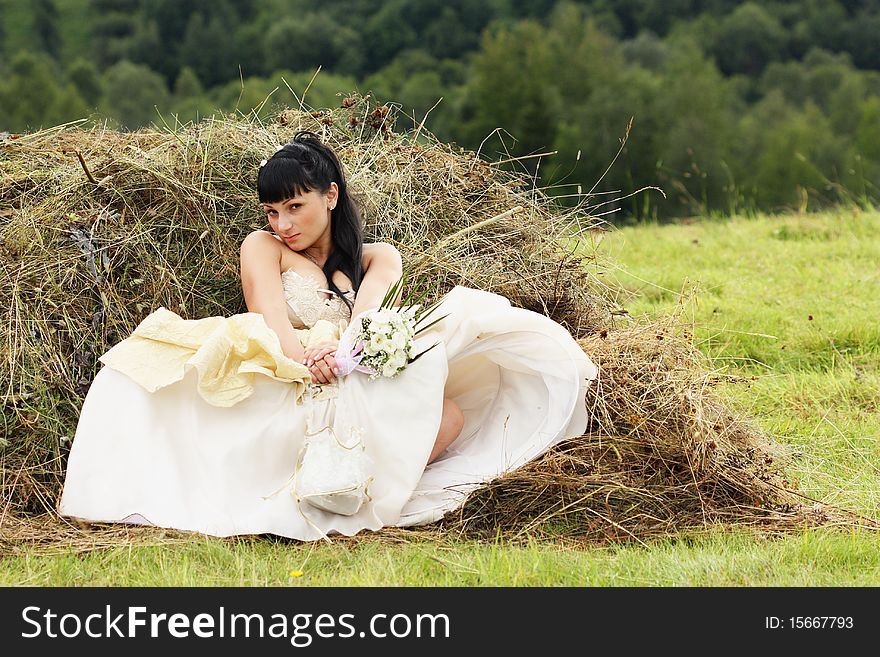 Beautiful bride relaxing in hay stack at her wedding day