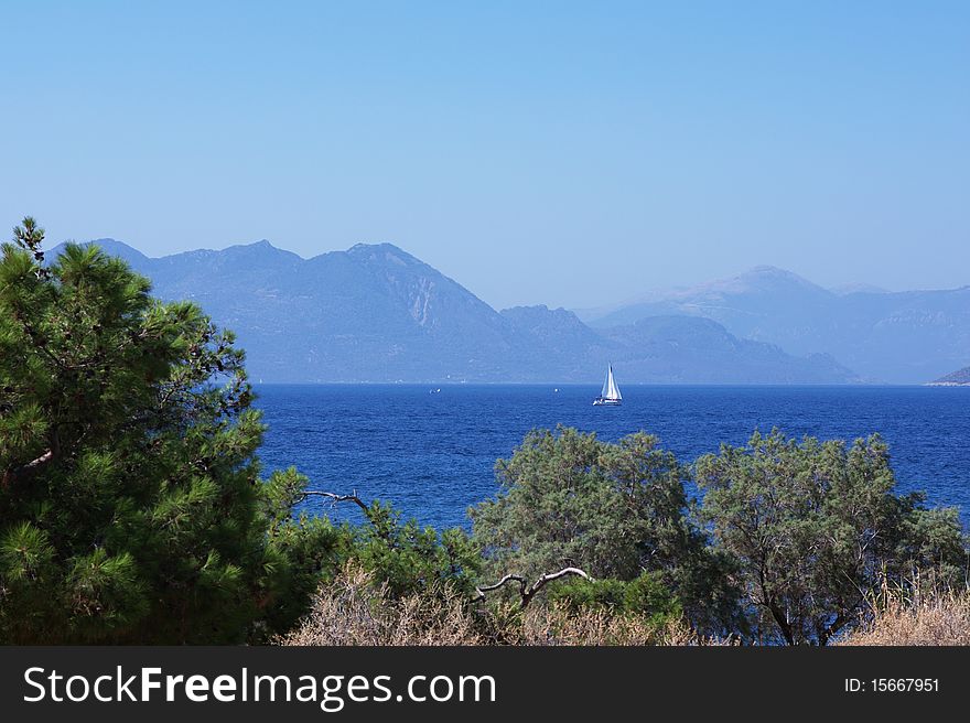 Mediterranean seascape with sea horizon, yacht and mountains