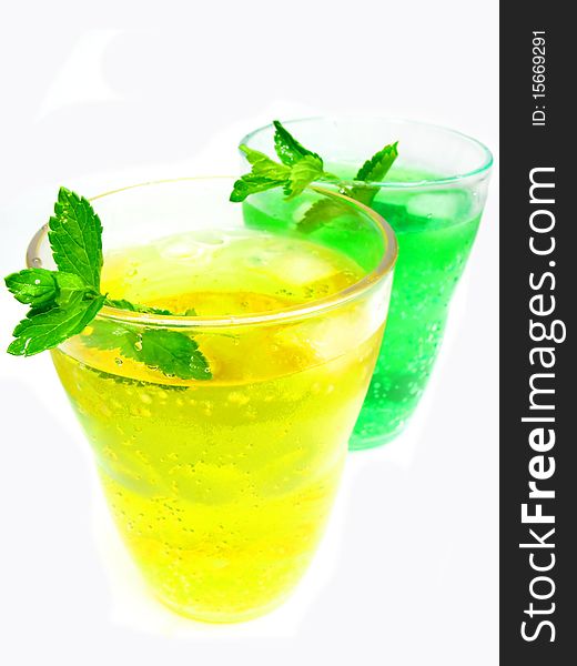 Two glasses of fruit green and yellow lemonade with ice and mint