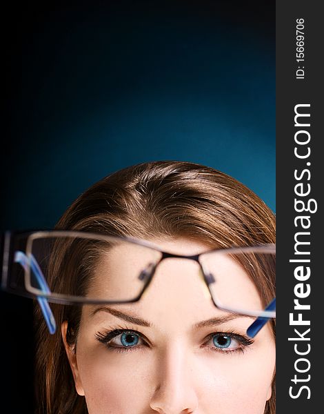 The upper half of a womans face looking at her glasses. Space for text. The upper half of a womans face looking at her glasses. Space for text.