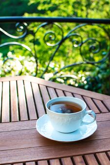 White Ceramic Cup Of Tea On A Saucer On Wooden Table Against Picturesque Background. Royalty Free Stock Image