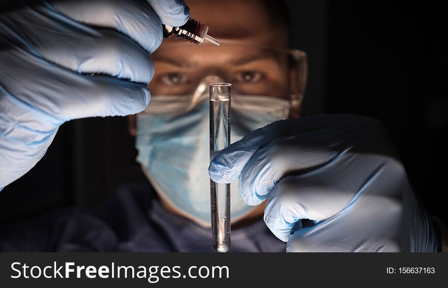 Male doctor in work uniform wearing gloves with goggles goggles examines in vitro analysis. Concept of: Proffessional doctor, Urine tests, Laboratory assistant, All protective kit.