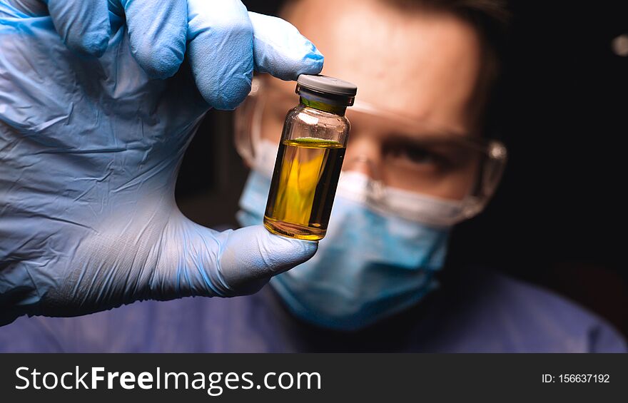 Male doctor in work uniform wearing gloves with goggles goggles examines in vitro analysis. Concept of: Proffessional doctor, Urine tests, Laboratory assistant, All protective kit.