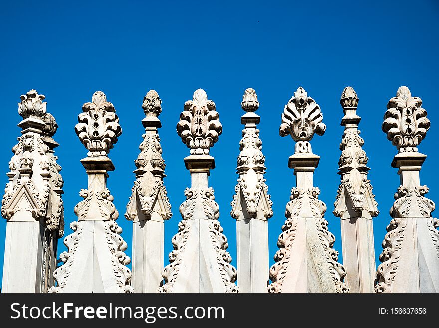 Close up of spires and statues on the roof of Duomo Milan Cathedral, Italy over the blue sky background. Close up of spires and statues on the roof of Duomo Milan Cathedral, Italy over the blue sky background.