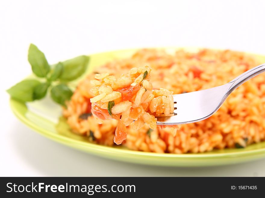 Risotto with tomatoes on a green plate decorated with basil - some of it on a fork