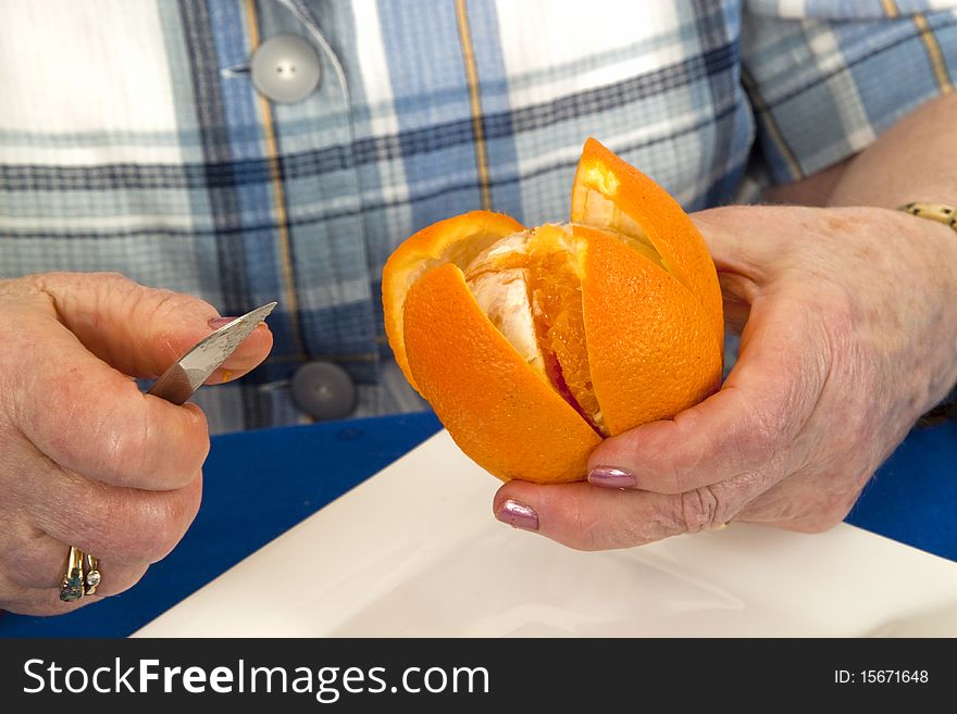 Detail from elderly woman peeling an orange - isolated on white background. Detail from elderly woman peeling an orange - isolated on white background