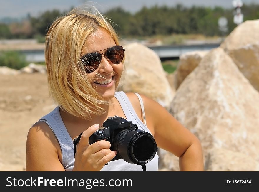 Blonde woman in sunglasses with a camera.