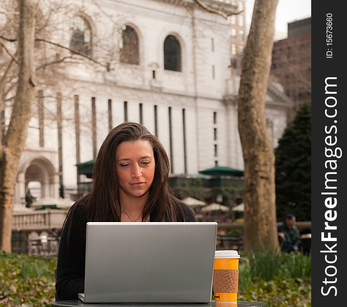 Beautiful woman seated with a laptop computer in a park. Beautiful woman seated with a laptop computer in a park.