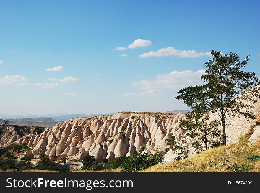 Cappadocia cliffs - astonishing natural landscape with great blue sky and some green trees around