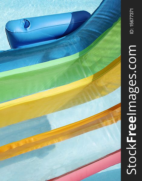 A close up of an inflatable rainbow colored chair in a swimming pool. A close up of an inflatable rainbow colored chair in a swimming pool