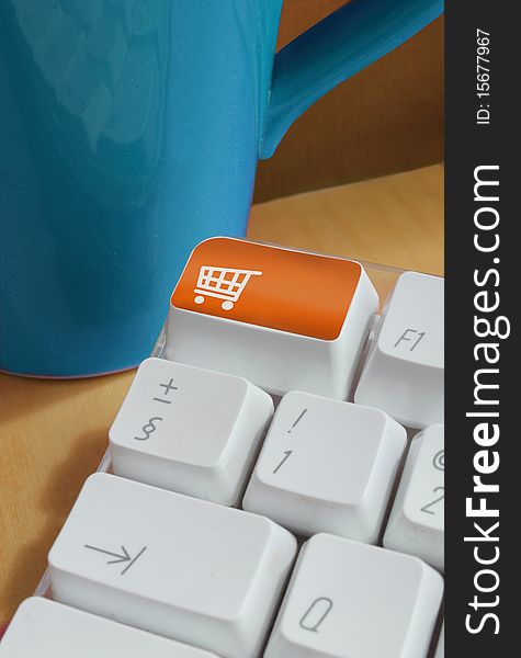 Shopping button on computer keyboard with mug in background on desk