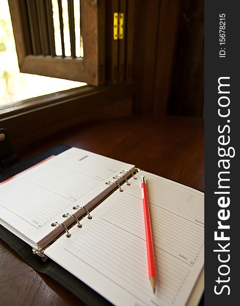 Blank notebook and pencil near window