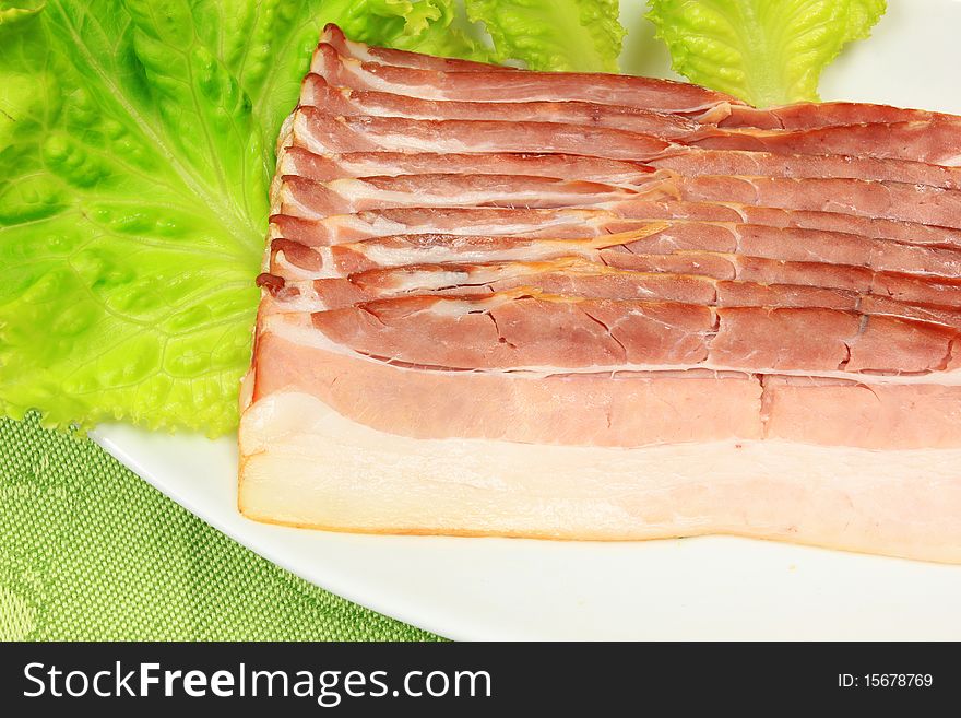 Slices of fresh bacon on white plate