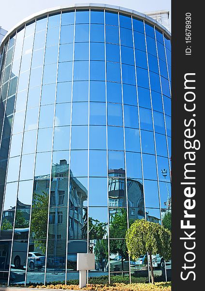 Front of a curved glass building with abstract reflections in the window. Front of a curved glass building with abstract reflections in the window