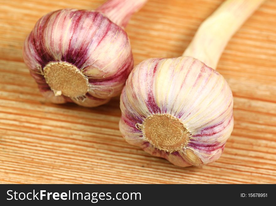 Whole violet garlic heads on wooden board. Whole violet garlic heads on wooden board