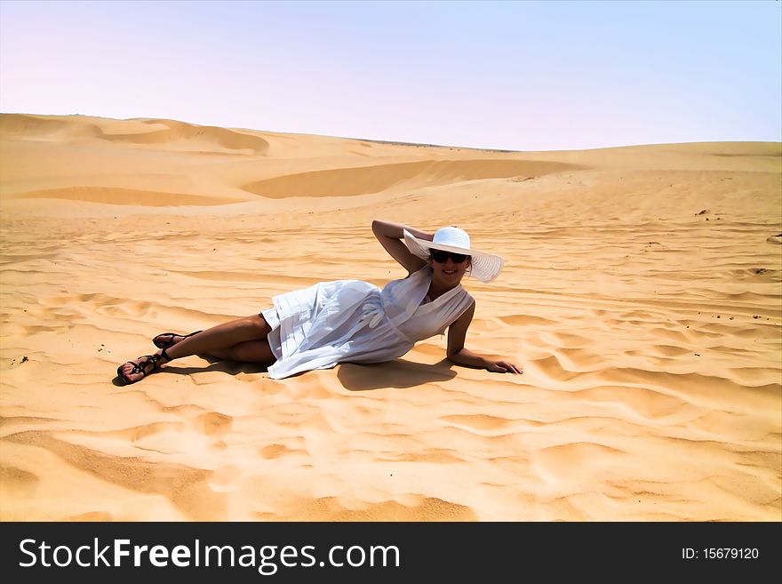 Girl in white dress and hat laying on the desert. Girl in white dress and hat laying on the desert
