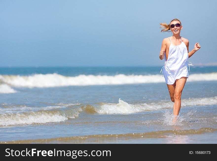 Young happy woman running in water on the beach. Sea shore. Young happy woman running in water on the beach. Sea shore