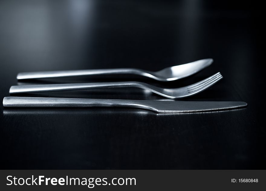 Silverware on black table (shallow DOF, focus on fork)