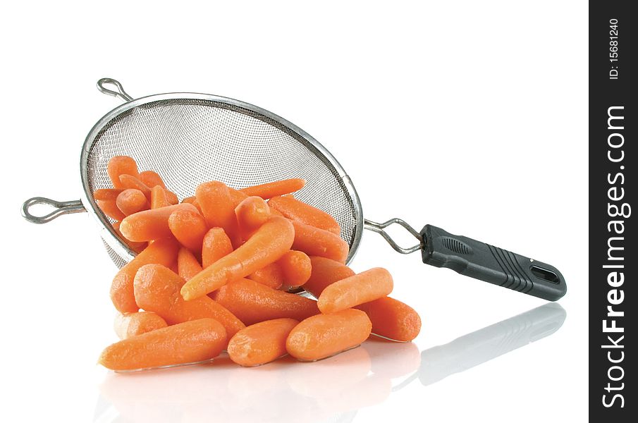 Freshly washed baby carrots spill from a kitchen strainer. Freshly washed baby carrots spill from a kitchen strainer