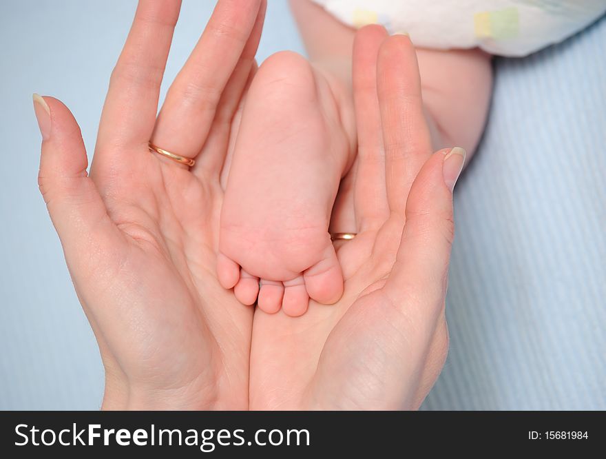 Mum holds a foot of the child in hands. Mum holds a foot of the child in hands