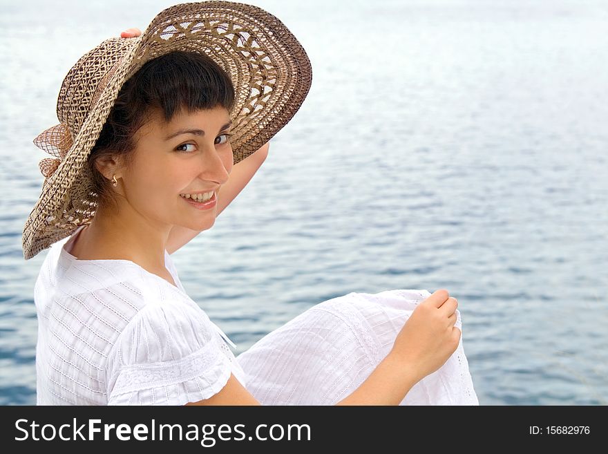 Happy young girl in the bonnet near the sea