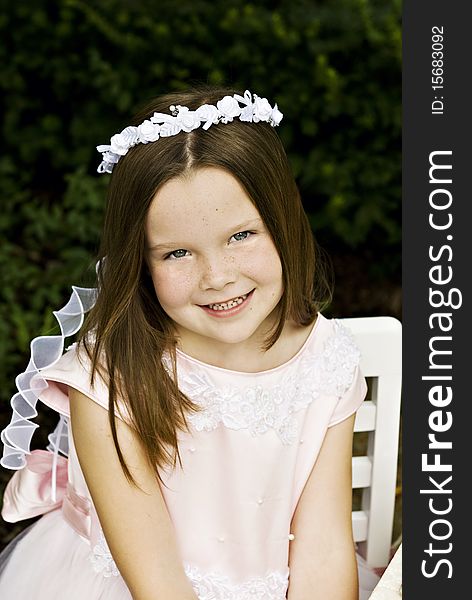 A smiling little six year old girl in a pretty pink dress, closeup with selective focus. A smiling little six year old girl in a pretty pink dress, closeup with selective focus