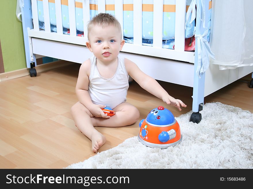 Little baby boy (1 year old) sitting on floor at children's room and playing with toys. Little baby boy (1 year old) sitting on floor at children's room and playing with toys