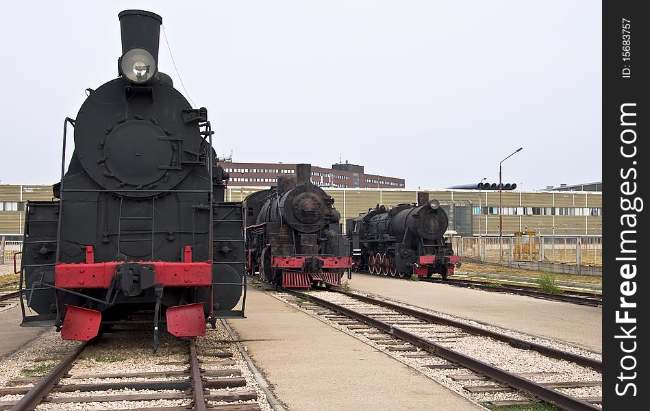 Steam locomotives beside a railway station platform. Retro train.