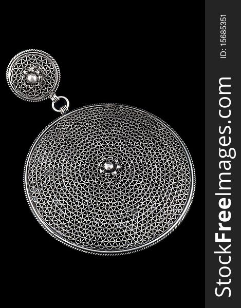 A decorative circular silver pendent isolated on a black background