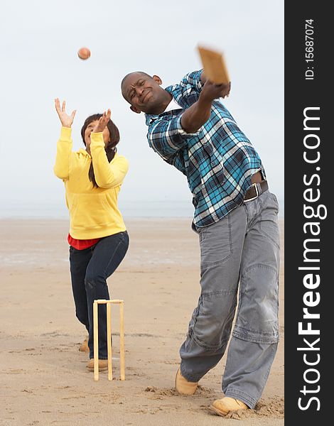 Young Couple Playing Cricket On Autumn Beach Holiday in the sun. Young Couple Playing Cricket On Autumn Beach Holiday in the sun