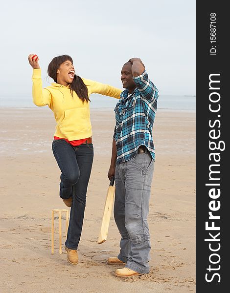 Young Couple Playing Cricket On Autumn Beach Holiday in the sun. Young Couple Playing Cricket On Autumn Beach Holiday in the sun