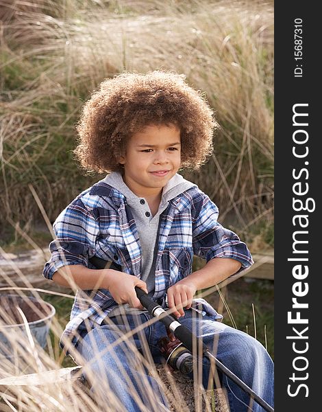 Young Boy Fishing At Seaside in the sun