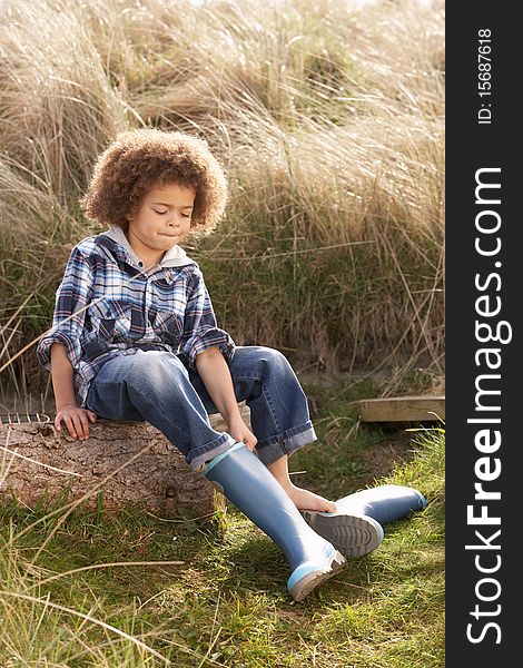 Young Boy Putting On blue Wellington Boots