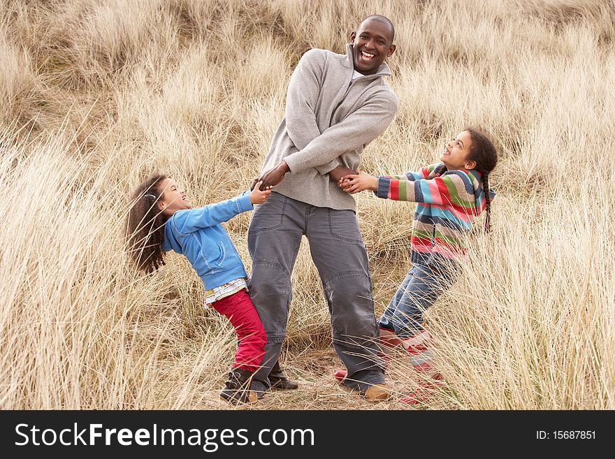 Father And Daughters Having Fun In Sand Dunes in the sun