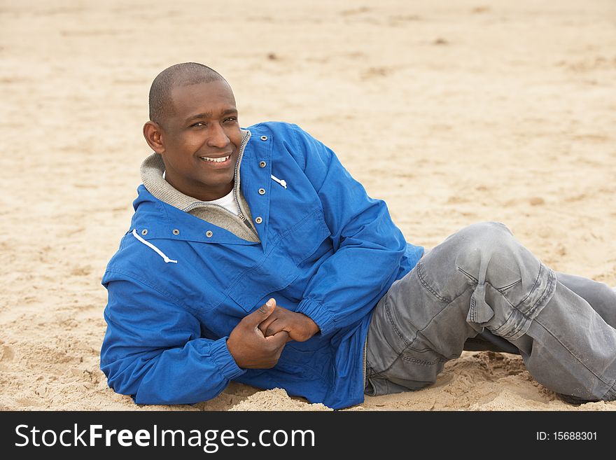 Man Relaxing On Beach In Autumn Clothing