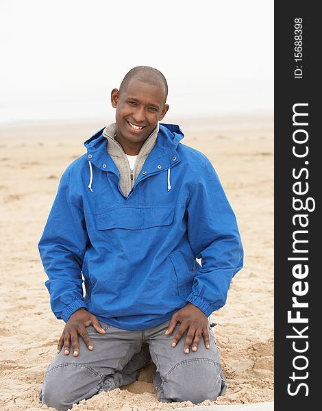 Man Relaxing On Beach In Autumn Clothing