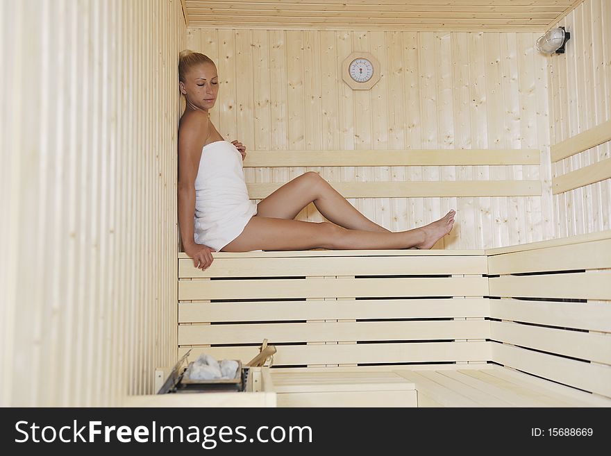 Young blonde beautiful woman in finland sauna warming up and healing in a spa wellness resort cabin. Young blonde beautiful woman in finland sauna warming up and healing in a spa wellness resort cabin