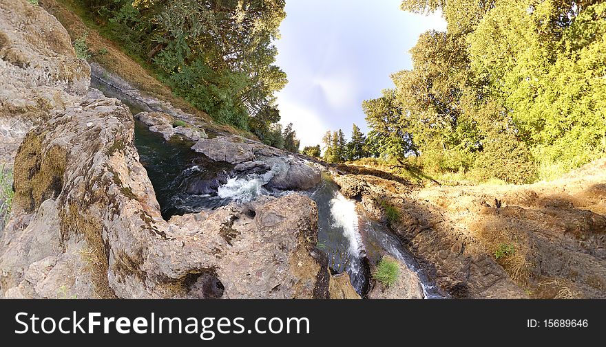 An earhtly rocky river with trees and sky with an extreme wide angle. An earhtly rocky river with trees and sky with an extreme wide angle