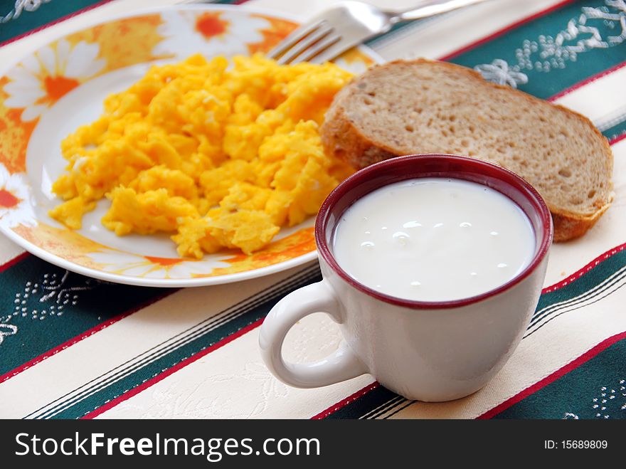 Yogurt in cup and scrambled eggs with bread served on table. Yogurt in cup and scrambled eggs with bread served on table