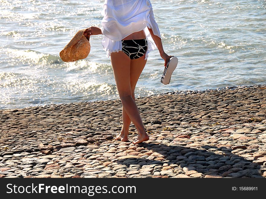 Woman in swim suit with hat walking on beach. Woman in swim suit with hat walking on beach