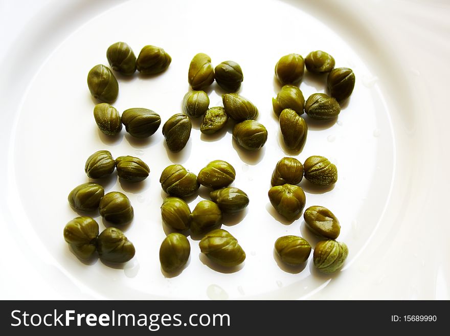 Sign of capers on white plate. Sign of capers on white plate