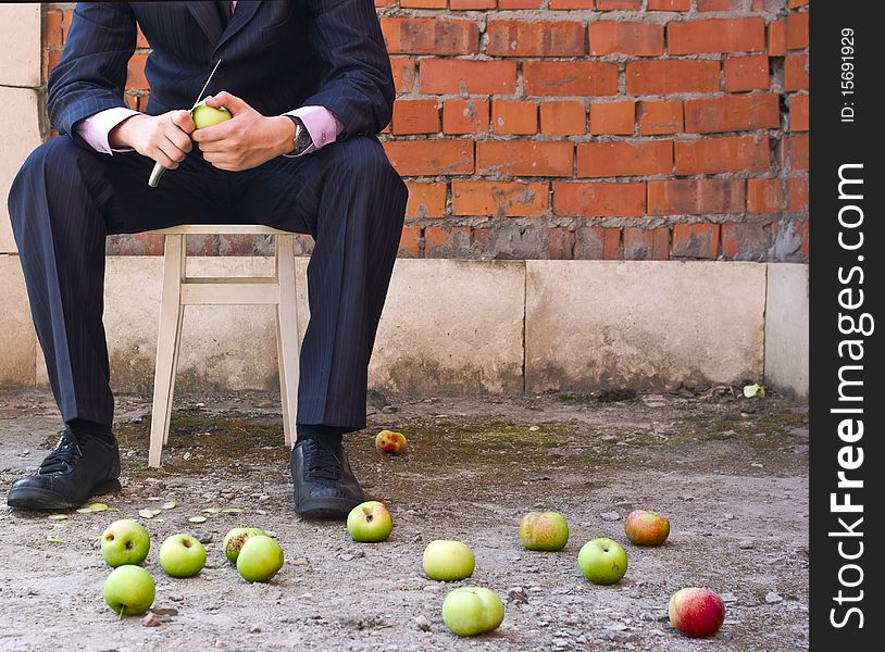 Businessman Cleaning Apples Sitting On A Stool