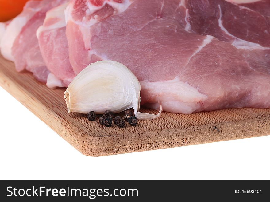 Piece of crude meat with garlic and black pepper on a kitchen board. Piece of crude meat with garlic and black pepper on a kitchen board.