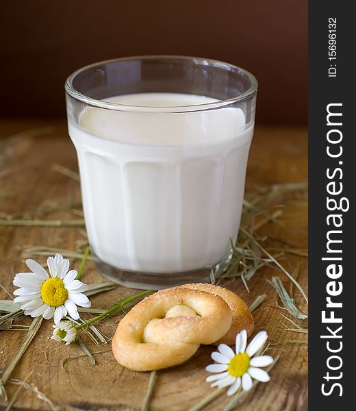 Glass of milk on a board with two cookies and chamomile