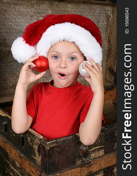 Young boy wearing a Christmas hat, sitting inside a trunk. Young boy wearing a Christmas hat, sitting inside a trunk