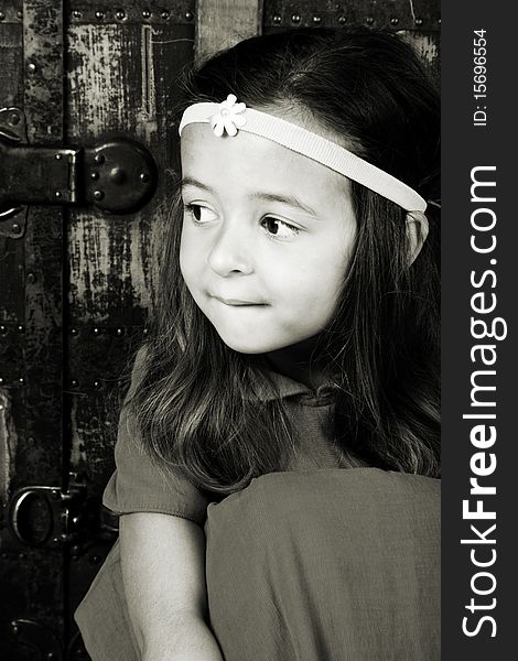 Cute brunette girl sitting against an antique trunk wearing a headband. Cute brunette girl sitting against an antique trunk wearing a headband