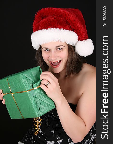 Beautiful brunette female wearing a christmas hat opening gifts. Beautiful brunette female wearing a christmas hat opening gifts