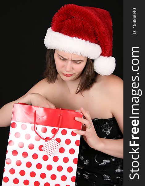 Beautiful brunette female wearing a christmas hat dissapointed with her gift. Beautiful brunette female wearing a christmas hat dissapointed with her gift