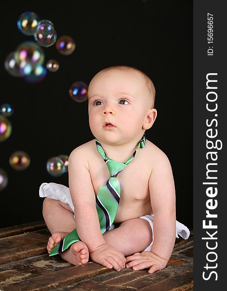 Cute baby boy sitting on an antique trunk looking at bubbles. Cute baby boy sitting on an antique trunk looking at bubbles